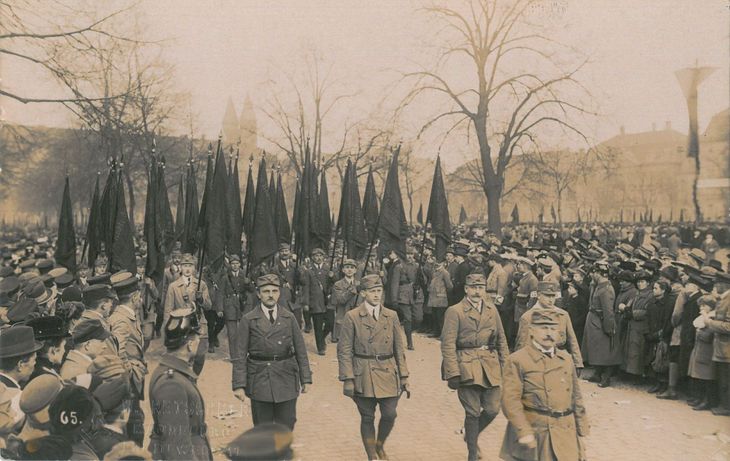 Historisches Schwarz-Weiß-Foto: durch eine große Menschenmenge scheitet eine Gruppe von Reichsbanner-Angehörigen mit Fahnen.