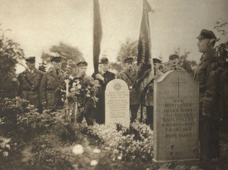 Historisches Schwarz-Weiß-Foto: Männer in Reichsbanner-Uniformen und Anzügen stehen mit Fahnen an einem Grab.