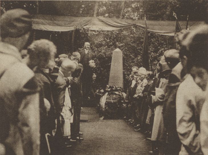 Historisches Schwarz-Weiß-Foto: Paul Hirsch steht neben einem mit einem Kranz geschmückten Gedenkstein und spricht zu den zahlreichen Anwesenden.